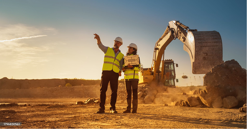 Toma de ingenieros civiles conversando al lado de excavadoras trabajando en el fondo