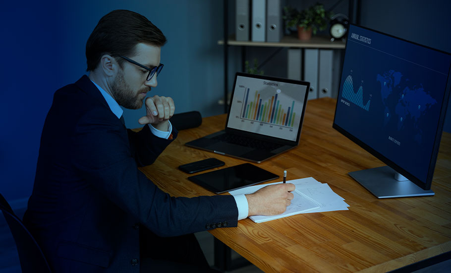 Ejecutivo trabajando y escribiendo en escritorio con notebook al costado