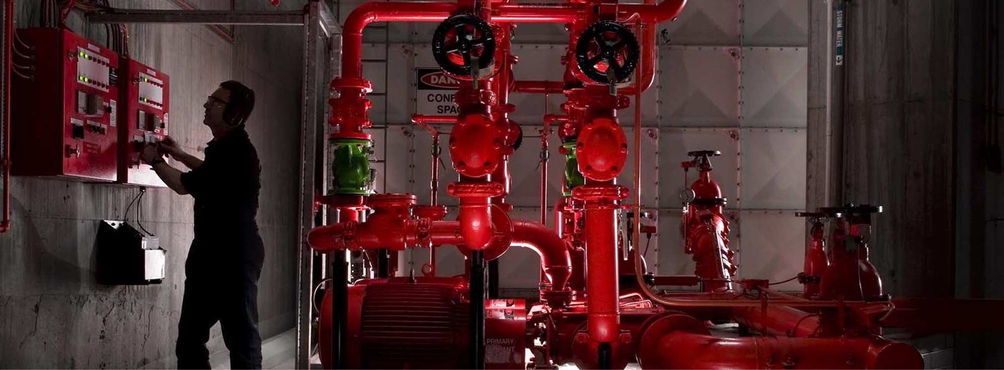 Plano de equipamiento y maquinarias donde se ven tuberías y manivelas que corresponden a instalación de equipo contra incendios y hombre trabajando en ellos